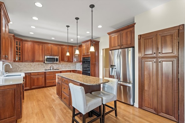 1396 Notre Dame Dr, Lemont, IL 60439 - kitchen featuring stainless steel appliances, a center island, brown cabinets, light wood-style floors, and tasteful backsplash