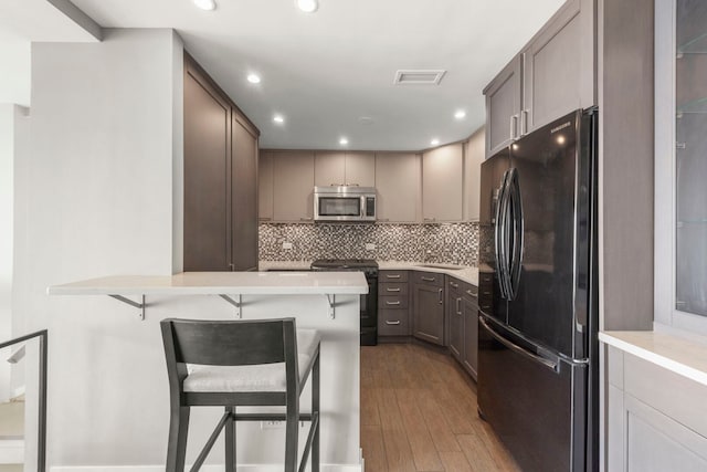 3200 N Lake Shore Dr N Unit 1910, Chicago, IL 60657 - kitchen featuring black appliances, a kitchen breakfast bar, wood finished floors, backsplash, and light countertops