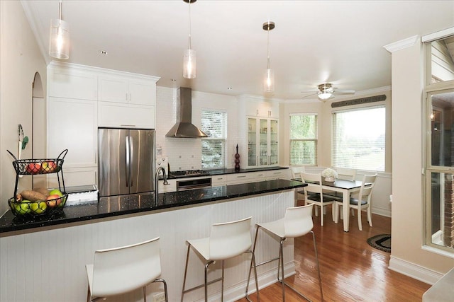 768 W St Johns Pl, Addison, IL 60101 - kitchen with freestanding refrigerator, wall chimney exhaust hood, white cabinetry, wood finished floors, and a kitchen breakfast bar