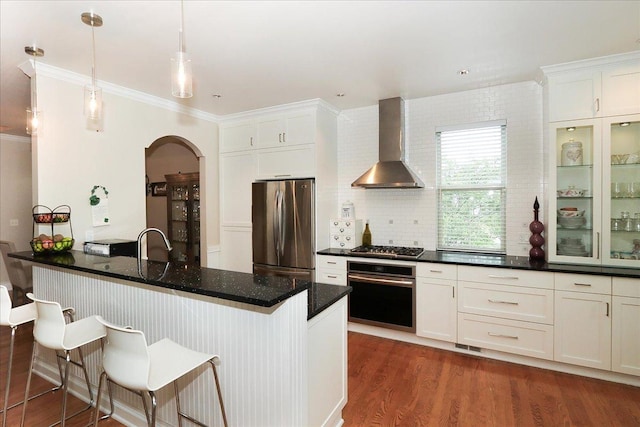 768 W St Johns Pl, Addison, IL 60101 - kitchen featuring appliances with stainless steel finishes, wall chimney range hood, white cabinetry, arched walkways, and crown molding