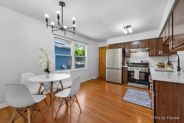 1422 Ridgeway St, Round Lake Beach, IL 60073 - kitchen with stainless steel appliances, under cabinet range hood, light wood-style floors, backsplash, and a chandelier