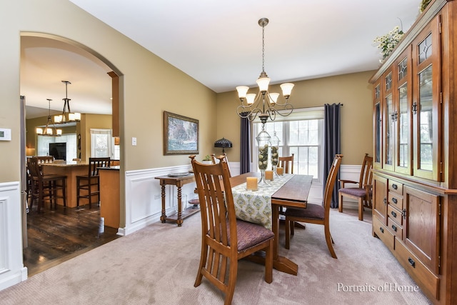 459 Waubonsee Cir, Oswego, IL 60543 - dining area featuring a chandelier, light colored carpet, wainscoting, arched walkways, and a decorative wall