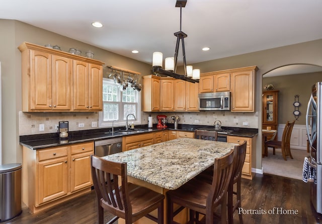 459 Waubonsee Cir, Oswego, IL 60543 - kitchen featuring stainless steel appliances, dark wood-type flooring, arched walkways, a kitchen bar, and dark stone counters