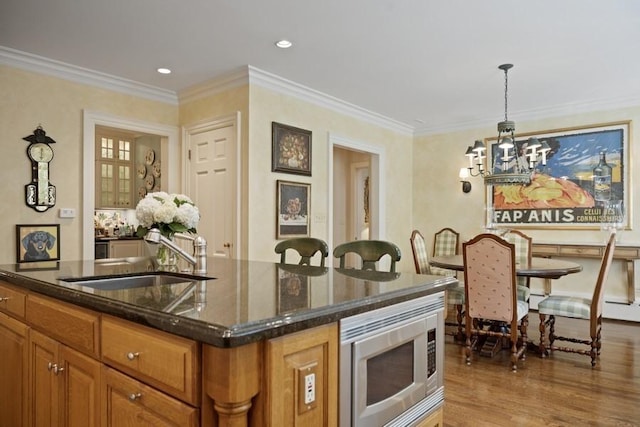 5 Woodley Rd, Winnetka, IL 60093 - kitchen featuring stainless steel microwave, a chandelier, light wood-style flooring, a kitchen island with sink, and brown cabinets
