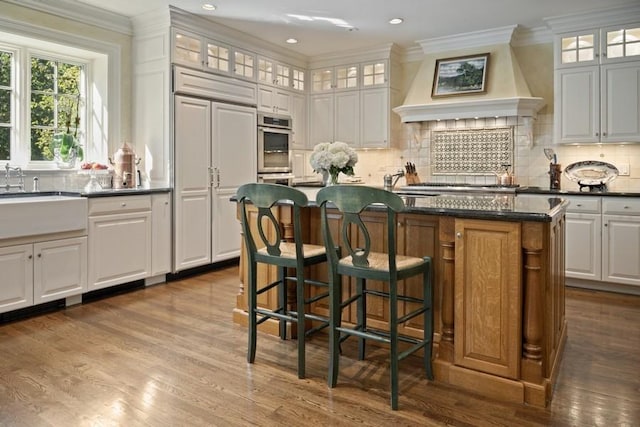 5 Woodley Rd, Winnetka, IL 60093 - kitchen featuring a center island, dark wood-type flooring, custom range hood, tasteful backsplash, and ornamental molding