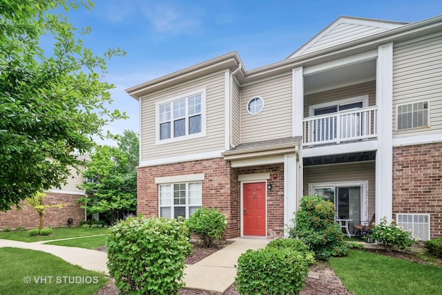 130 Clubhouse Ln Unit 029, Oswego, IL 60543 - view of front of home featuring a balcony, brick siding, and a front yard