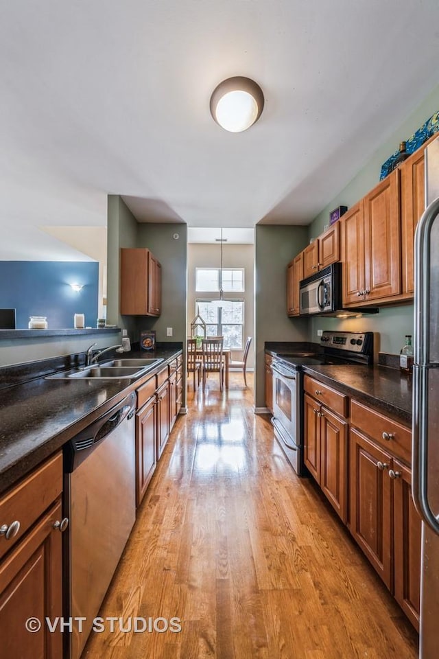 130 Clubhouse Ln Unit 029, Oswego, IL 60543 - kitchen with appliances with stainless steel finishes, dark countertops, light wood-style floors, and brown cabinets
