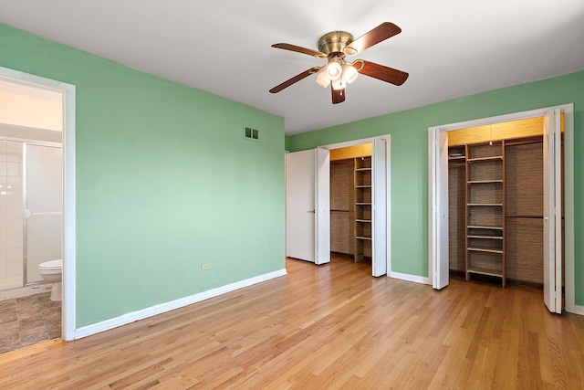 7617 Sycamore Dr, Orland Park, IL 60462 - unfurnished bedroom with multiple closets, light wood-type flooring, ensuite bath, and a ceiling fan