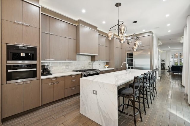 34 E Bellevue Pl, Chicago, IL 60611 - kitchen with hardwood / wood-style flooring, a chandelier, an island with sink, tasteful backsplash, and light stone counters