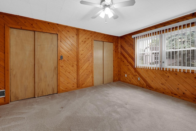 8201 Paloma Dr, Orland Park, IL 60462 - unfurnished bedroom featuring carpet, multiple closets, wooden walls, and ceiling fan