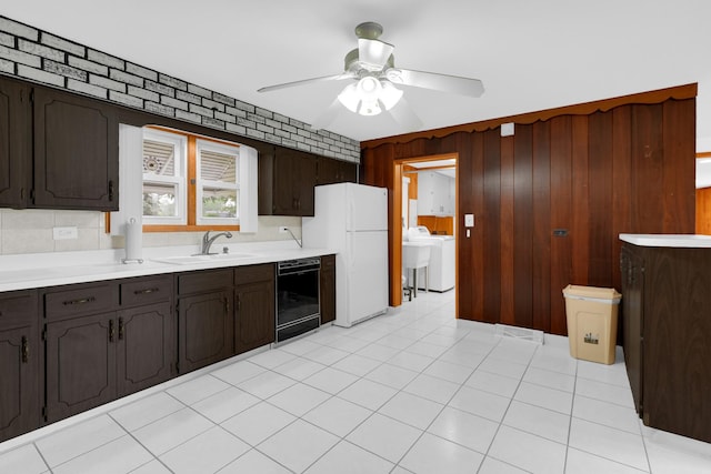 8201 Paloma Dr, Orland Park, IL 60462 - kitchen with freestanding refrigerator, washer / dryer, dark brown cabinets, black dishwasher, and wood walls