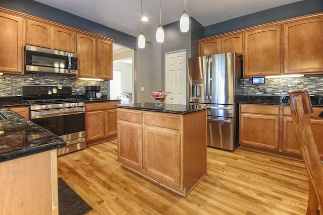 8307 Newbridge Ct, Joliet, IL 60431 - kitchen featuring stainless steel appliances, light wood-style floors, backsplash, a kitchen island, and dark stone countertops