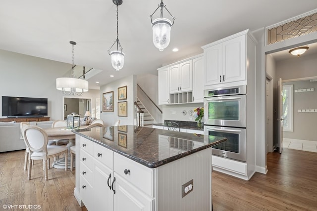25397 N Northbridge Rd, Hawthorn Woods, IL 60047 - kitchen featuring stainless steel double oven, a kitchen island, dark stone countertops, light wood-style floors, and white cabinets
