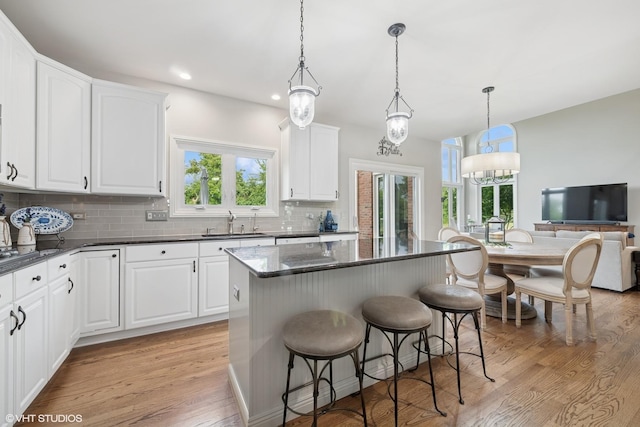 25397 N Northbridge Rd, Hawthorn Woods, IL 60047 - kitchen featuring a breakfast bar area, backsplash, light wood-style floors, white cabinets, and a kitchen island
