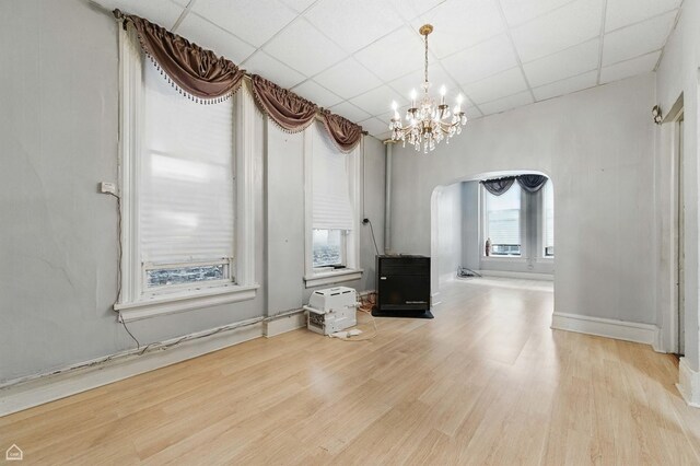 1448 W Taylor St, Chicago, IL 60607 - unfurnished living room with arched walkways, a paneled ceiling, a chandelier, and wood finished floors