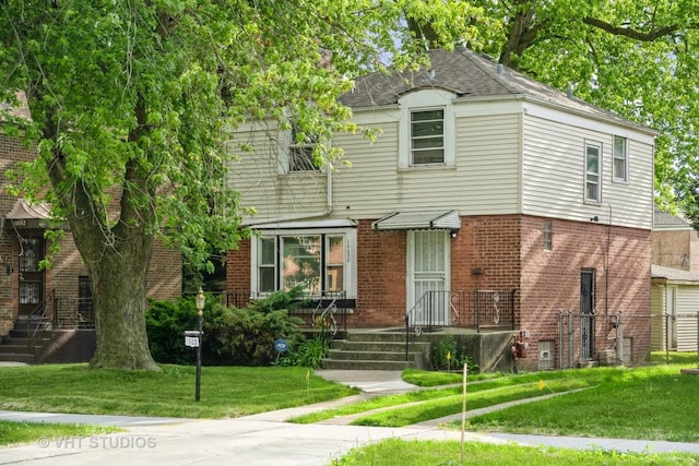 view of front of property with brick siding, a front lawn, and roof with shingles