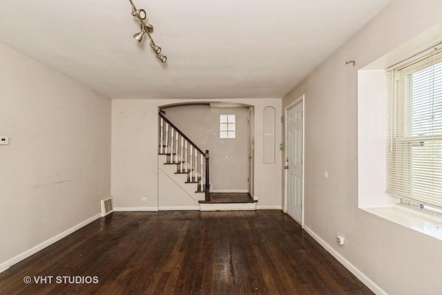entrance foyer with hardwood / wood-style flooring, stairway, and arched walkways