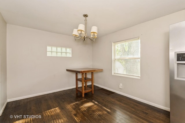 unfurnished dining area featuring dark wood-type flooring and a chandelier
