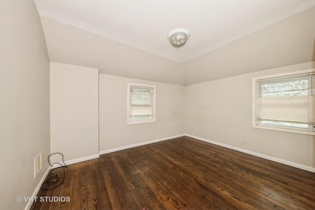 additional living space with healthy amount of natural light, dark wood finished floors, and lofted ceiling