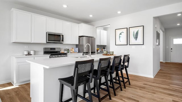 1818 Legacy Pointe Blvd, Plainfield, IL 60586 - kitchen with appliances with stainless steel finishes, light wood-style floors, a kitchen island with sink, light countertops, and a breakfast bar