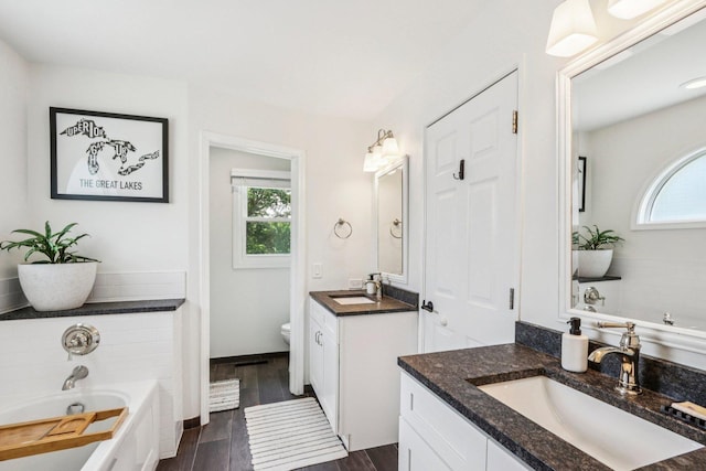 7004 Bennington Dr, Gurnee, IL 60031 - full bathroom featuring plenty of natural light, a garden tub, two vanities, and wood finished floors