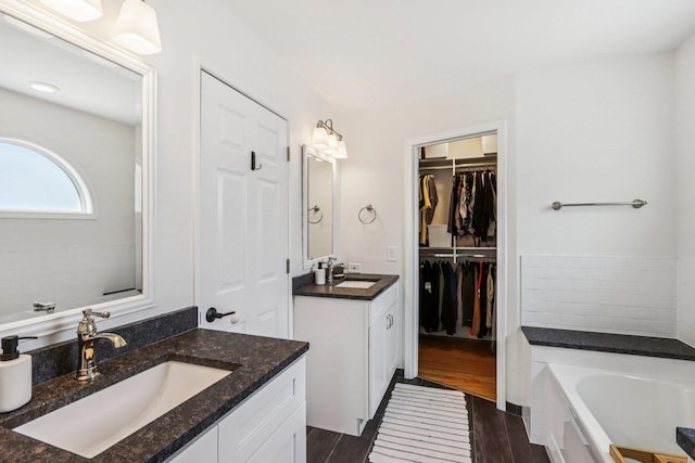 7004 Bennington Dr, Gurnee, IL 60031 - bathroom featuring a bath, wood finished floors, two vanities, and a walk in closet