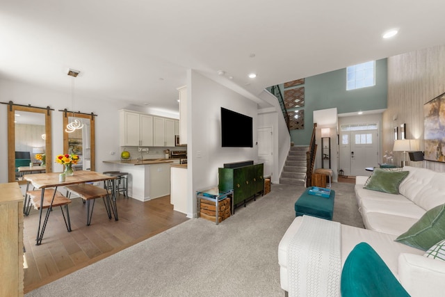 1580 Wind Energy Pass, Batavia, IL 60510 - living area featuring a barn door, stairs, recessed lighting, light wood-type flooring, and a towering ceiling