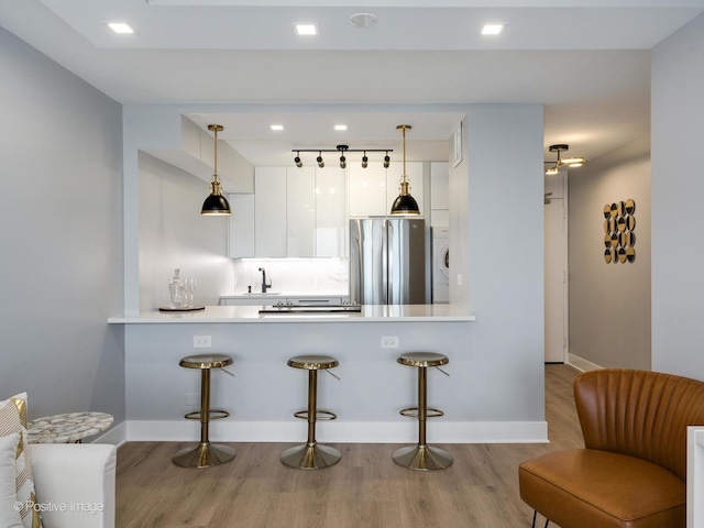 1560 N Sandburg Ter Unit 2403J, Chicago, IL 60610 - kitchen with freestanding refrigerator, wood finished floors, a kitchen breakfast bar, white cabinetry, and a peninsula