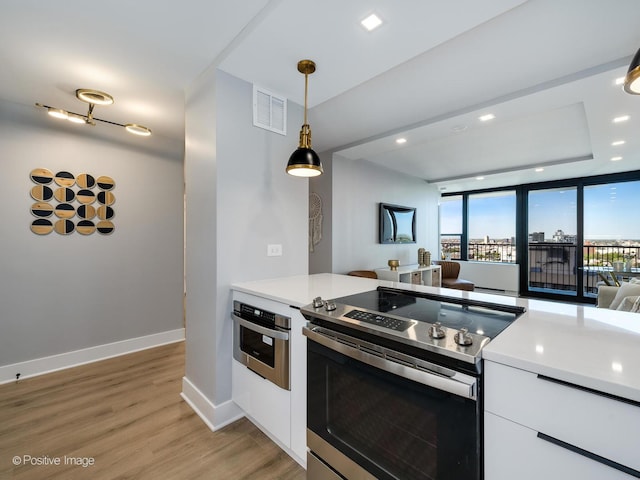 1560 N Sandburg Ter Unit 2403J, Chicago, IL 60610 - kitchen with stainless steel appliances, white cabinets, light wood-style flooring, hanging light fixtures, and light countertops