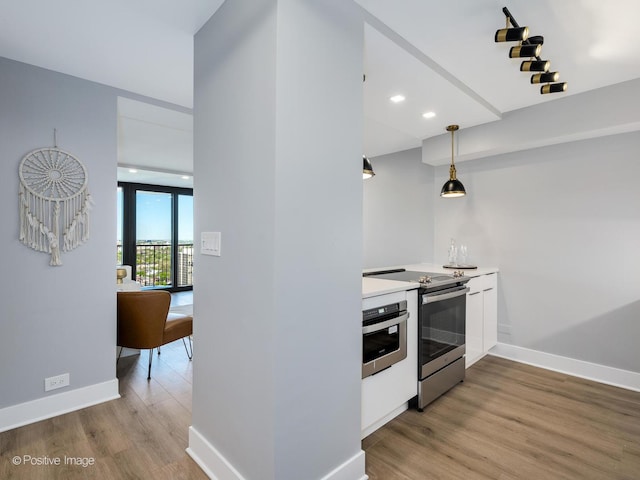 1560 N Sandburg Ter Unit 2403J, Chicago, IL 60610 - kitchen with appliances with stainless steel finishes, light wood finished floors, light countertops, decorative light fixtures, and white cabinetry