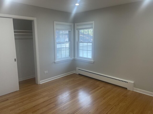 1530 S Greenwood Ave, Park Ridge, IL 60068 - unfurnished bedroom with a baseboard heating unit, light wood-type flooring, and a closet