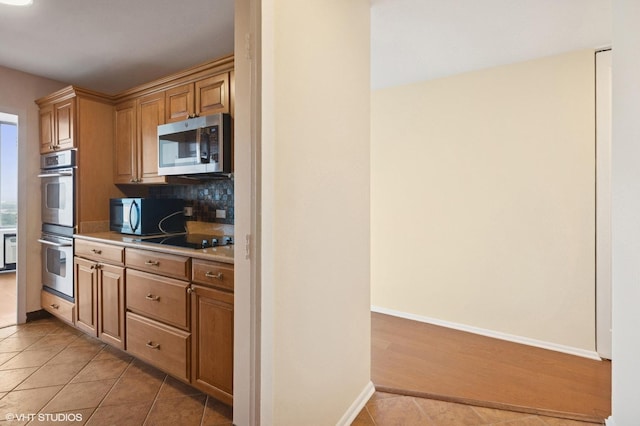 5757 N Sheridan Rd Unit 20J, Chicago, IL 60660 - kitchen featuring appliances with stainless steel finishes, light countertops, light tile patterned floors, backsplash, and brown cabinets