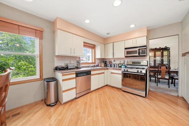 1125 Charlene Ln, Schaumburg, IL 60193 - kitchen featuring stainless steel appliances, decorative backsplash, light wood-style flooring, white cabinetry, and light countertops