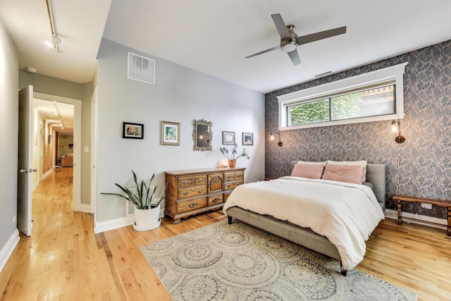 4611 N Magnolia Ave Unit 2, Chicago, IL 60640 - bedroom with wallpapered walls, light wood finished floors, rail lighting, an accent wall, and a ceiling fan