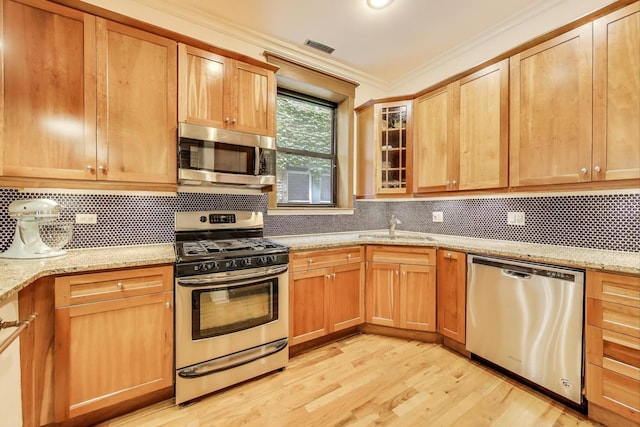 4611 N Magnolia Ave Unit 2, Chicago, IL 60640 - kitchen featuring appliances with stainless steel finishes, light wood-type flooring, tasteful backsplash, crown molding, and light stone countertops