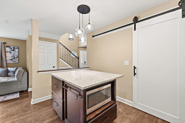 10750 Cape Cod Ln, Huntley, IL 60142 - kitchen with a barn door, stainless steel microwave, dark brown cabinets, and wood finished floors