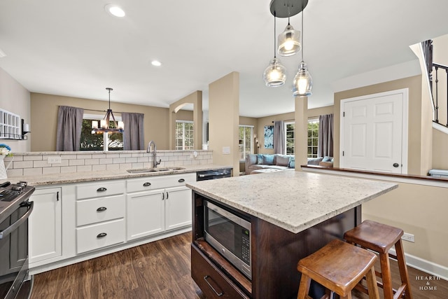 10750 Cape Cod Ln, Huntley, IL 60142 - kitchen featuring appliances with stainless steel finishes, dark wood finished floors, white cabinets, light stone counters, and a breakfast bar area