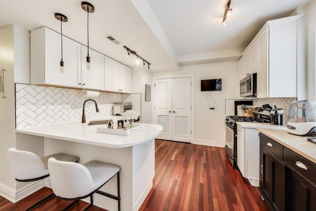 1918 W Cullom Ave Unit 202, Chicago, IL 60613 - kitchen with stainless steel appliances, rail lighting, tasteful backsplash, white cabinetry, and a peninsula