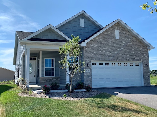 27357 W Porto Ln, Channahon, IL 60410 - craftsman house with a garage, asphalt driveway, a front lawn, brick siding, and a porch