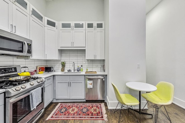 1847 N Kedzie Ave Unit 1N, Chicago, IL 60647 - kitchen with stainless steel appliances, decorative backsplash, light countertops, dark wood-style flooring, and glass insert cabinets