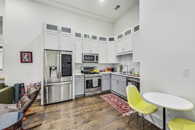 1847 N Kedzie Ave Unit 1N, Chicago, IL 60647 - kitchen featuring stainless steel appliances, dark wood finished floors, gray cabinetry, tasteful backsplash, and glass insert cabinets