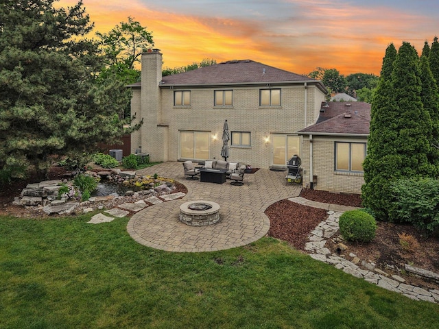 102 E Adelia St, Elmhurst, IL 60126 - back of property at dusk with an outdoor living space with a fire pit, a patio, a yard, a chimney, and brick siding