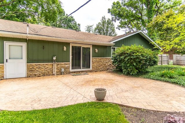 2458 E Cass St, Joliet, IL 60432 - rear view of property with stone siding, a patio area, board and batten siding, and a shingled roof