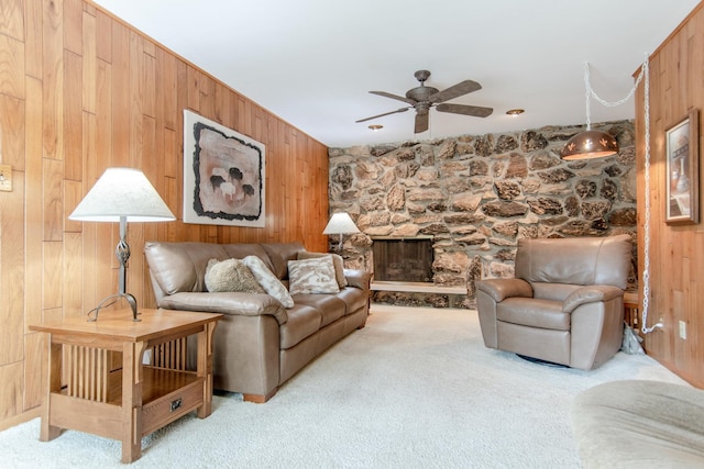2458 E Cass St, Joliet, IL 60432 - living area featuring wooden walls, light colored carpet, a ceiling fan, and a stone fireplace