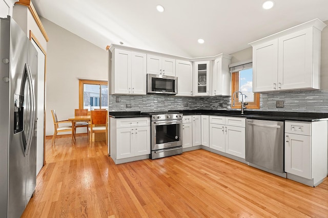 3800 River Rd, Hazel Crest, IL 60429 - kitchen with appliances with stainless steel finishes, vaulted ceiling, dark countertops, decorative backsplash, and light wood finished floors