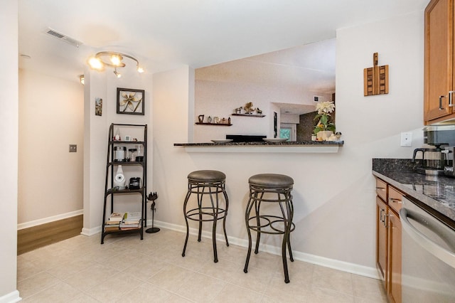 845 E 22nd St Unit 219, Lombard, IL 60148 - kitchen with stainless steel dishwasher, brown cabinets, a kitchen breakfast bar, dark stone counters, and light tile patterned flooring
