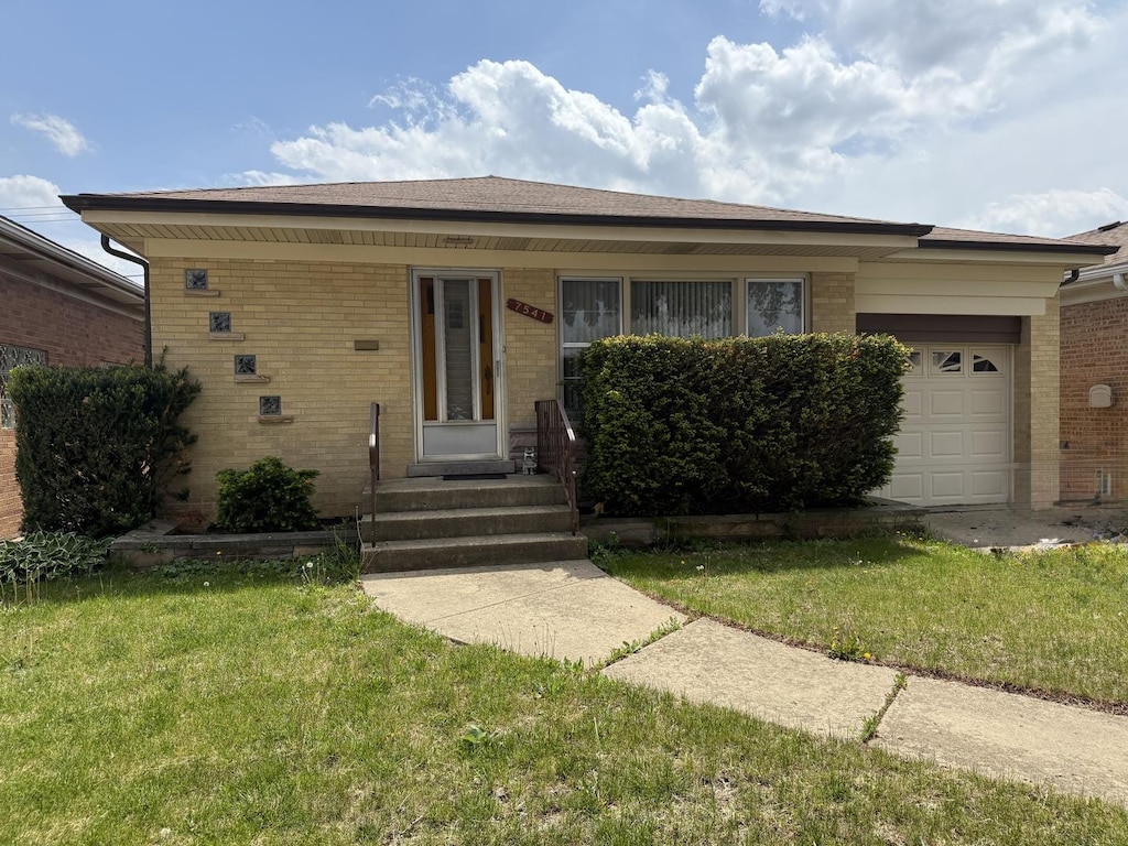 single story home with brick siding, a garage, and a front yard