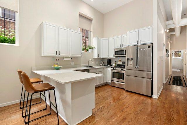 1217 N Greenview Ave Unit G, Chicago, IL 60642 - kitchen with stainless steel appliances, a high ceiling, a peninsula, plenty of natural light, and white cabinets