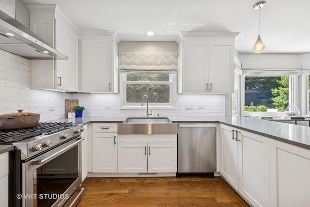 821 Sandstone Dr, Libertyville, IL 60048 - kitchen featuring stainless steel appliances, wall chimney range hood, white cabinetry, decorative backsplash, and pendant lighting