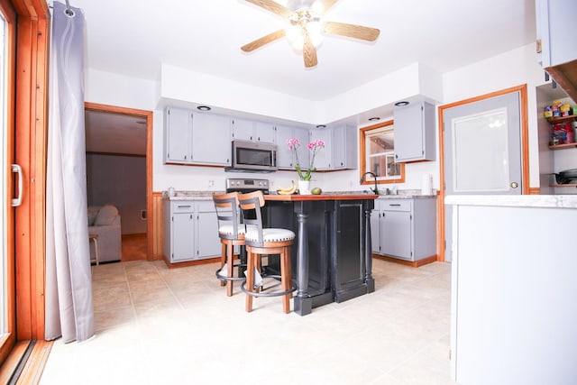 382 Keigwin Rd, Walnut, IL 61376 - kitchen with stainless steel appliances, light countertops, a ceiling fan, gray cabinetry, and a breakfast bar area